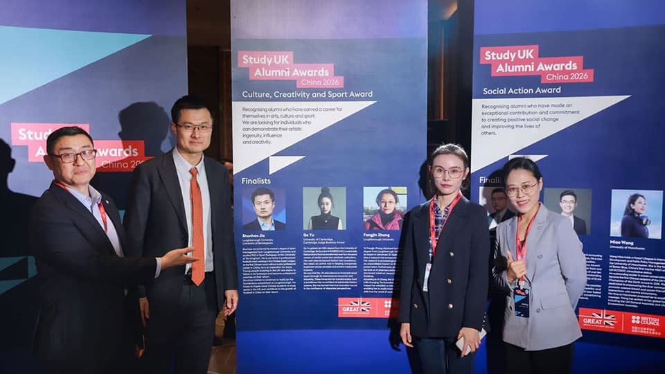 Study UK Awards branding on banners behind them. Winner Shunhao and Virginia standing together at the awards ceremony in China along with other finalists and they are all smiling.